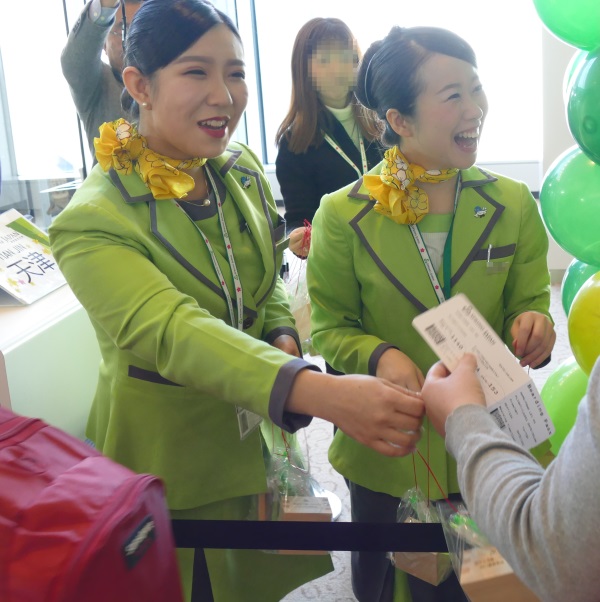 天津行きの初便の乗客に記念品を配る春秋航空日本の客室乗務員