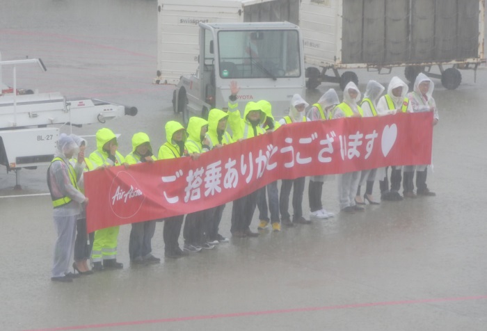 雨の中 横断幕を掲げるスタッフ